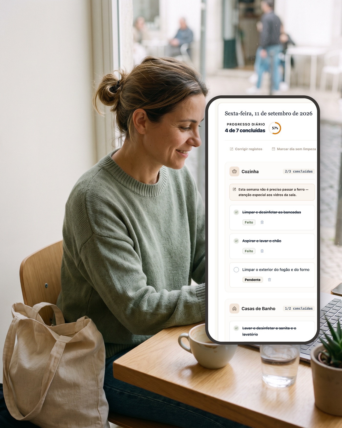 Mulher num café a ver no telemóvel a lista do dia da Empregada app, com o progresso e as tarefas marcadas